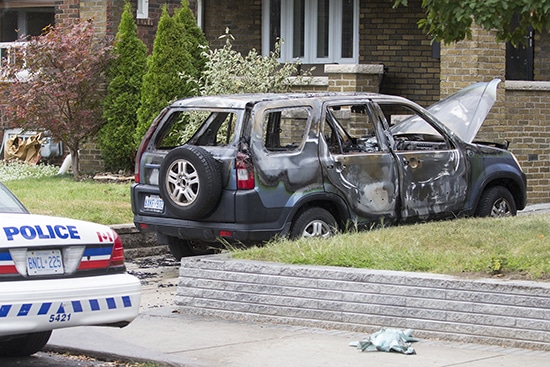 Police secure the scene of a car fire along Strathmore Boulevard, one of six arson attacks that included porch and garbage fires lit in the early morning hours of Wednesday, Sept. 9. PHOTO: Andrew Hudson