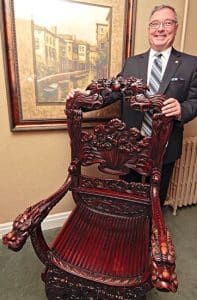 Nick Larter, funeral director at Sherrin Funeral Home, stands by the antique chair that will continue to be a Beach conversation piece when it moves to the Williams cottage in Kew Gardens. PHOTO: Andrew Hudson