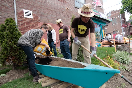 “Park Rangers” Ting Wang, right, and Aidan Nolan, centre, help make a canoe into a garden planter full of native pollinator plants on May 22 outside a coffee shop at Rhodes Avenue and Gerrard Street East. Part of the David Suzuki Foundation’s Homegrown National Park project, it is the 12th garden canoe to mark the buried waterways flowing under Toronto streets, and the first one in the East End.