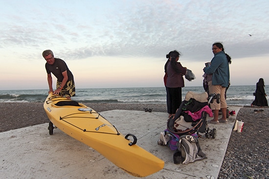Mark Kremblewski wheels his kayak home at sunset last Saturday using a new pathway that parks staff installed earlier this month at Woodbine Beach. “It’s very difficult to wheel on the sand, so having this come right to the water is fantastic,” he said, adding that the path is already a hit for families with strollers and early-morning walkers who don’t want sand in their shoes. PHOTO: Andrew Hudson