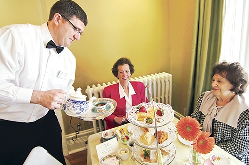 Rotarian James Green serves Mother's Day tea to Marilyn Pepper, centre, and her mother Barbara, right, at the Gardener's Cottage in Kew Gardens on Saturday, May 11. This year's Mother's Day Tea went ahead with special provisions: the second floor was closed to the public, and mobile washrooms were set up outside. Members of the Kew Cottage advisory council have sent a letter to Toronto Fire Services asking whether community events might continue at the cottage with special event permits. PHOTO: Andrew Hudson