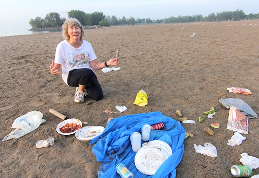 Artist Elizabeth Berry, left, wearing a T-shirt with a print of her painting Woodbine Beach Litter (above) and the slogan 'Pick Me Up At the Beach', stands by a cluster of litter on Woodbine Beach early on the morning of Aug. 30. PHOTO: Andrew Hudson