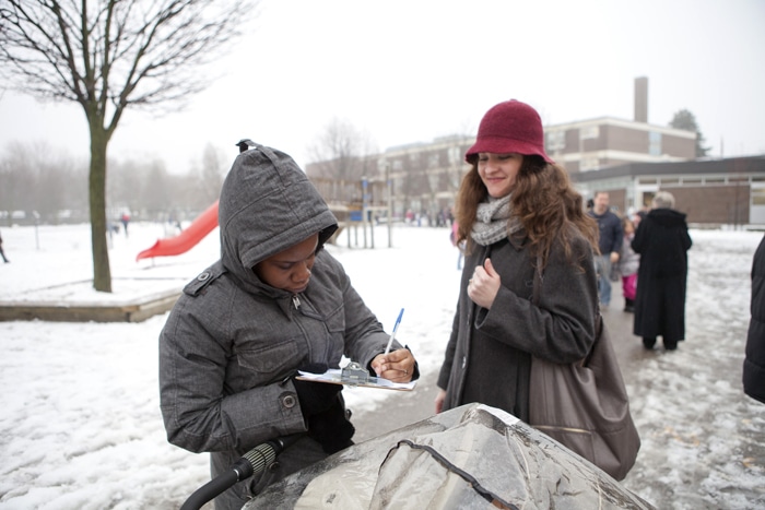 Nakesha Nelson signs a petition from organizer Swarna Banerjee. Parents gathered signatures on Jan. 28 at Secord Public School to have TDSB put the school on a priority list for funding for upgrades. PHOTO: Phil Lameira / Beach Metro News